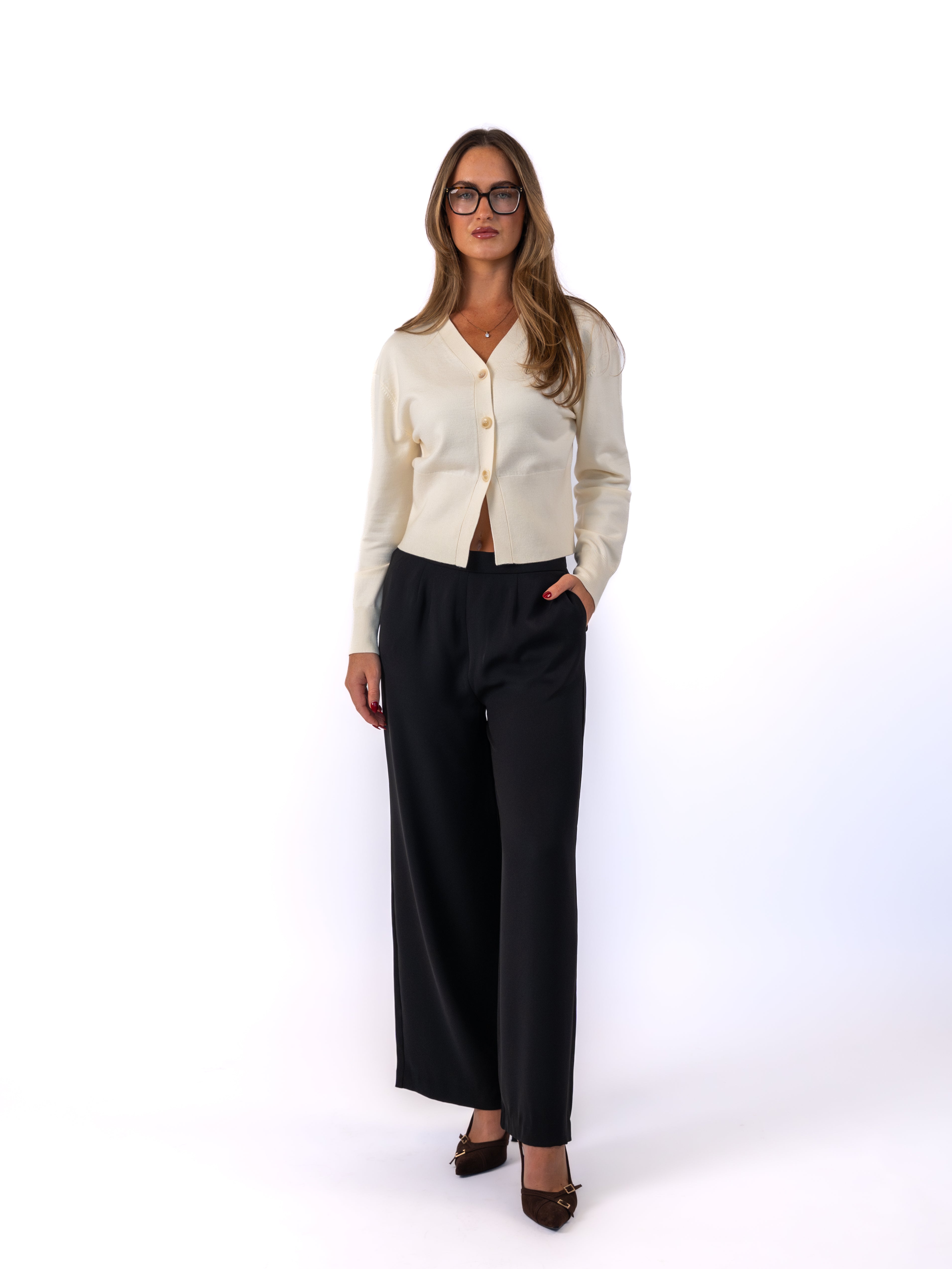 Person wearing a white sweater and black pants against a plain background