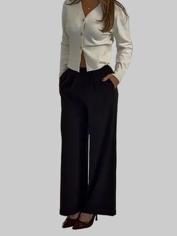 Person wearing a white sweater and black pants against a plain background